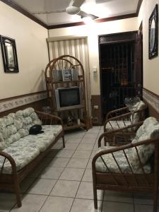 a living room with a couch and chairs and a tv at Ruiselares in Puntarenas