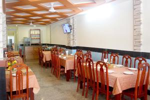 a dining room with tables and chairs and a television at Ha Anh Hotel - Mui Ne in Mui Ne