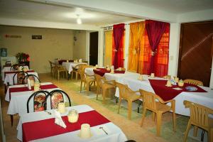 a restaurant with white tables and chairs and red curtains at Hotel Milenio Nanacamilpa Tlaxcala in Nanacamilpa