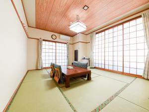 a living room with a table and chairs and large windows at Tanegashima Araki Hotel in Nishinoomote