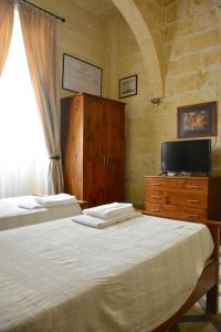 a bedroom with two beds and a tv and a dresser at Xemx in Qala
