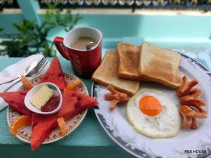 a plate of breakfast food with eggs and toast and a cup of coffee at Pek House in Phuket