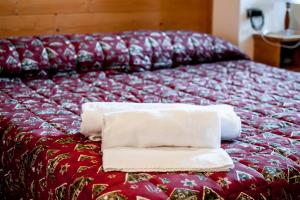 a bed with two towels sitting on top of it at Albergo Riglarhaus in Sauris