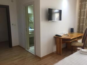 ein Hotelzimmer mit einem Schreibtisch und einem TV an der Wand in der Unterkunft Lyabi House Hotel in Buxoro