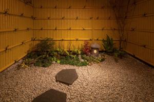 a room with a yellow wall with plants and rocks at Yukari Kyoto in Kyoto