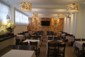 Candango Aero Hotel في برازيليا: مطعم بطاولات وكراسي وجدار من الطوب