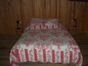 ein Bett mit einer roten und weißen Bettdecke darauf in der Unterkunft Chambre d'hôte Domaine de Bois joli in Buis-les-Baronnies