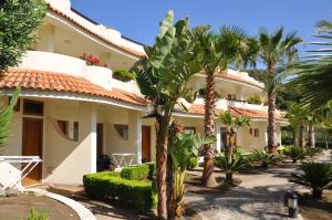 a large house with palm trees in front of it at Hotel Scoglio Del Leone in Zambrone