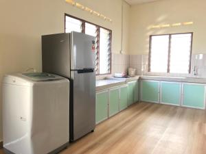 a large kitchen with a refrigerator and a sink at SingSport Holiday House in Mersing