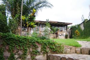 a house with a palm tree and a stone wall at VAYA APARTMENTS Kiriri with Panoramic View in Bujumbura