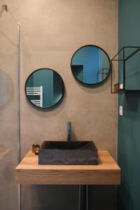 a bathroom with a sink and two mirrors on the wall at Hotel Des Arts in Wimereux