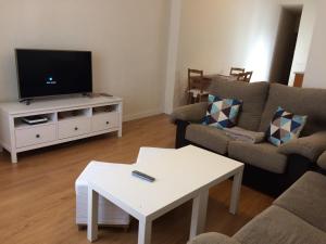 un soggiorno con una TV, un divano e un tavolo di Peris Mencheta a Siviglia