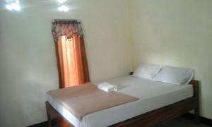 Pedek Homestay في برايا: سرير في غرفة مع ستارة برتقال