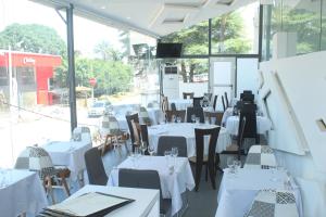 a restaurant with white tables and chairs and windows at residence Amann appartement et spa Hammam Sauna jacuzzi in Marcory