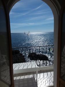 a view of the ocean from a balcony with a sailboat at Hotel Orpheus in Giardini Naxos