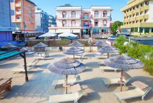 - un groupe de chaises et de parasols dans une cour dans l'établissement Hotel Sara, à Rimini