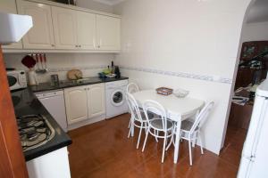 una pequeña cocina con mesa blanca y sillas en Casa Barrela I, en Tavira