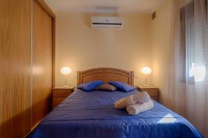 a bedroom with a bed with blue sheets and two lamps at Casa do Penedo in Tangil