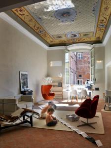 un bambino seduto sul pavimento in un soggiorno con soffitto di La Finestra Guest Apartment - Eco&Bio a Lucca