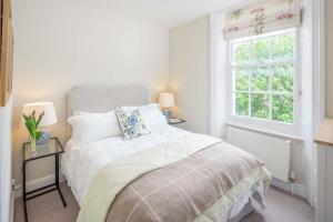 - une chambre blanche avec un lit et une fenêtre dans l'établissement Bright flat for 6, near Victoria and Warwick square, à Londres