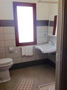 La salle de bains est pourvue de toilettes, d'un lavabo et d'une fenêtre. dans l'établissement B&B Campu Moru, à Bari Sardo