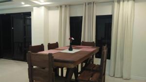 a dining room table with a vase of flowers on it at The Guest House Laoag in Laoag