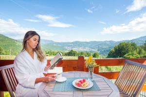 a woman sitting at a table with a plate of food at Hotel & Resort Gacka in Mojkovac