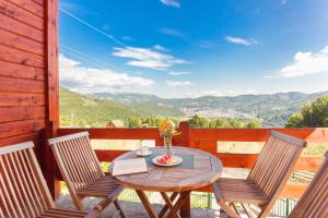 un tavolo in legno con sedie e un balcone con vista. di Hotel & Resort Gacka a Mojkovac