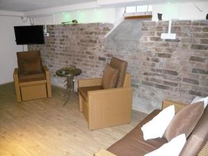 a living room with chairs and a brick wall at Pension am Weinberg in Mesenich