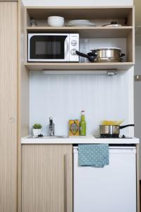 a kitchen with a sink, microwave, and dishwasher at Aparthotel Adagio Access Bruxelles Europe Aparthotel in Brussels