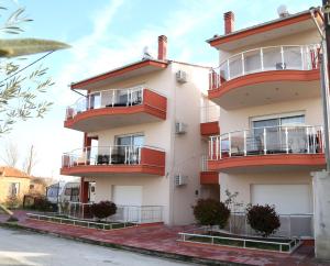 ein Gebäude mit roten Balkonen auf einer Straße in der Unterkunft Sinanis Family Apartments in Keramotí