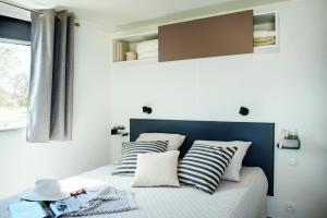 ein kleines Schlafzimmer mit einem Bett mit gestreiften Kissen in der Unterkunft Camping Village Città di Milano in Mailand