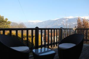 a balcony with two chairs and a table and mountains at Chez Philippe in Savièse