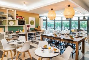 un restaurant avec des tables, des chaises et des fenêtres dans l'établissement Aparthotel Adagio Access Paris Vanves - Porte de Châtillon, à Vanves