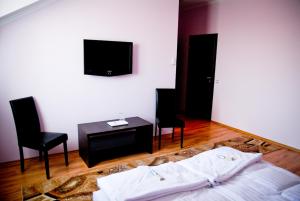 um quarto com uma cama e duas cadeiras e uma televisão em Pazonyi Fogadó és Étterem em Nyírpazony