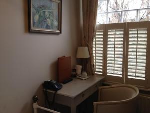 a room with a desk with a telephone and a window at Balham Lodge in London