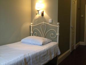 a bedroom with a white bed with a light on the wall at Balham Lodge in London