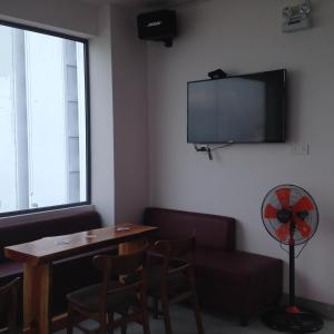 a room with a table and a tv on the wall at Bondi Backpackers Nhatrang in Nha Trang
