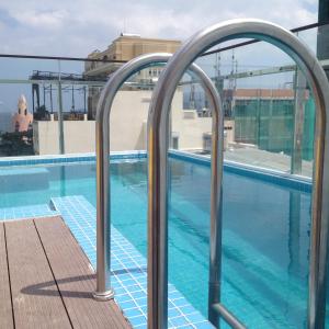 a swimming pool with metal hand rails next to a building at Bondi Backpackers Nhatrang in Nha Trang