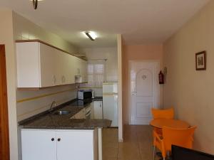 una cocina con armarios blancos y una silla naranja en Apartamentos Olympia Garden, en La Manga del Mar Menor