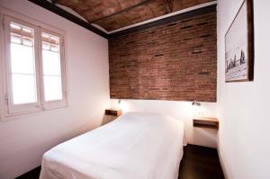 バルセロナにあるBarceloneta Suites Apartments Beachの白いベッドとレンガの壁が備わるベッドルーム1室が備わります。