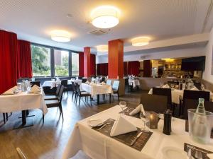 un restaurante con mesas y sillas blancas y ventanas en DORMERO Hotel Hannover en Hannover