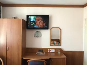 een kamer met een tv aan de muur en een bureau bij Miles Hotel Berlin in Berlijn