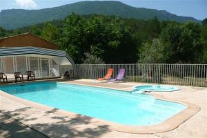 a swimming pool with two chairs and a fence at Domaine de bois joli in Buis-les-Baronnies