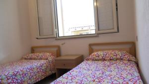 two beds in a small room with a window at Casa Vacanze La Bandera 1 in Santa Teresa Gallura
