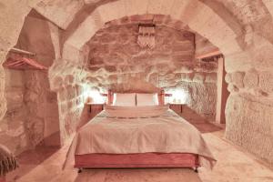 a bedroom with a bed in a stone wall at Mosaic Cave Hotel in Göreme