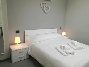 a white bedroom with a white bed with a heart on it at Lingotto Residence in Turin
