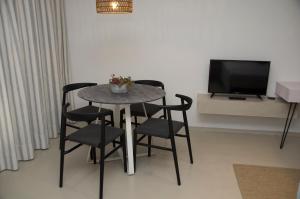 a table and chairs in a living room with a television at Hylatio Tourist Village in Pissouri