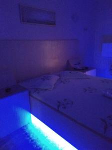 a bedroom with a white bed with a blue light at Hotel Jardim América ( Adults only) in São Paulo