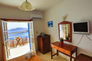 a living room with a television and a room with a table at Armonia by Grispos Villas in Schinoussa